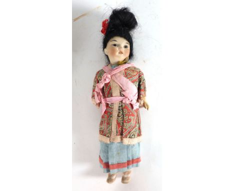 A Schoenau & Hoffmeister bisque headed oriental doll having fixed brown glass eyes, painted features and open mouth showing f