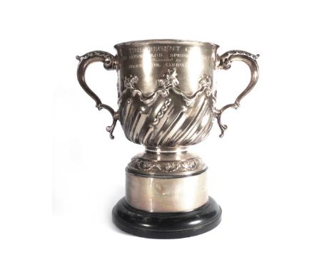 A late Victorian silver two handled trophy vase of cylindrical form, the pair of leaf capped c-scroll handles above a gadroon