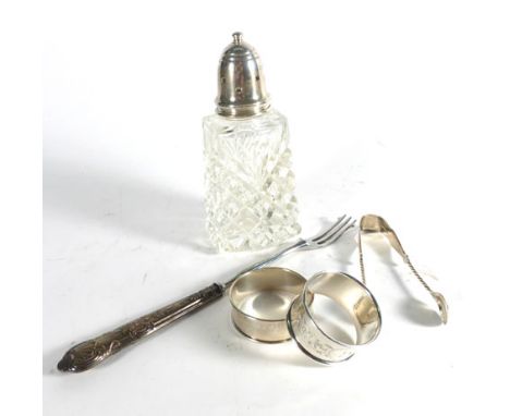 A mixed group of silver comprising a mounted sugar sifter, two napkin rings, a pair of sugar tongs and a silver handled toast