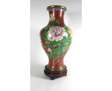 A cloisonne enamel vase of bellied form decorated with flowering dahlia on a terracotta ground, on a carved hardwood stand, o