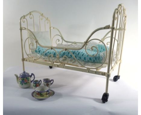 A cream painted metalwork doll's crib, l. 45 cm, together with a crocheted blanket and a miniature doll's tea service