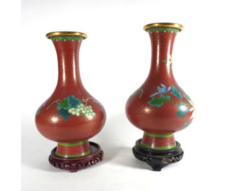 A pair of cloisonne enamel vases of bellied form decorated with flowering chrysanthemum on a terracotta ground, each on a car