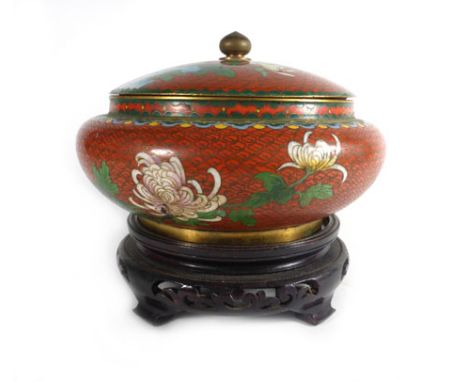 A cloisonne enamel bowl and cover of squat bun shaped form decorated with flowering chrysanthemum on a terracotta ground, on 