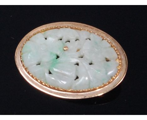 A carved celadon jade oval brooch as leaves and flowers, in yellow metal mount, stamped 750, 3.5 x 2.5cm