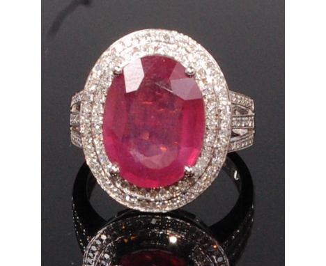 A contemporary 14ct white gold, ruby and diamond dress ring, the four claw set oval cut ruby weighing approx 6.9ct, in a two-