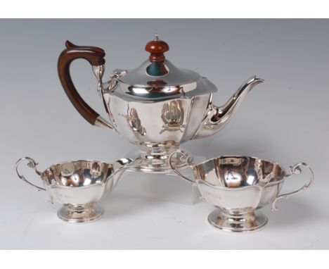 A silver three piece teaset, comprising pedestal teapot, twin handled sugar and cream, the teapot with walnut handle and fini