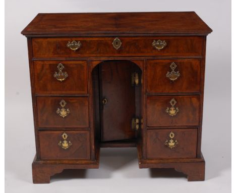 A mid-18th century walnut kneehole desk, having a cross and feather banded four quarter veneered top above an arrangement of 