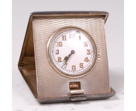 An Art Deco silver cased travel clock/watch, the engine turned case with hinge action, by Horace Woodward & Co, assayed 1921,