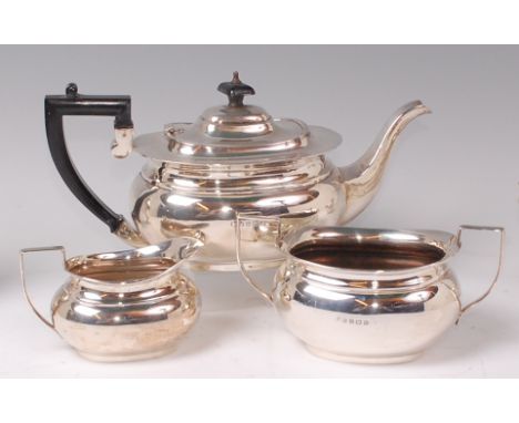 A George V silver three piece teaset, comprising; teapot, twin handled sugar and cream, each of oval bombe form, the teapot w