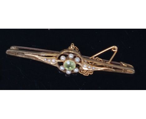 An Edwardian 15ct gold, green peridot and seed pearl set bar brooch, with safety chain, 4.3g, w.5.4mm