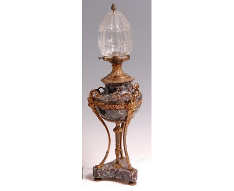 A late 19th century French gilt metal and variegated marble table lamp, of urn form, the heavy geometric clear glass shade ov