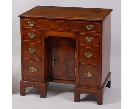 A yew wood kneehole writing desk, in the mid-18th century style, having arrangement of seven drawers flanking centre cupboard