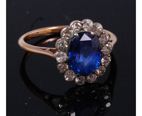 An early 20th century yellow metal, sapphire and diamond cluster ring, the centre claw set oval cut sapphire weighing approx 