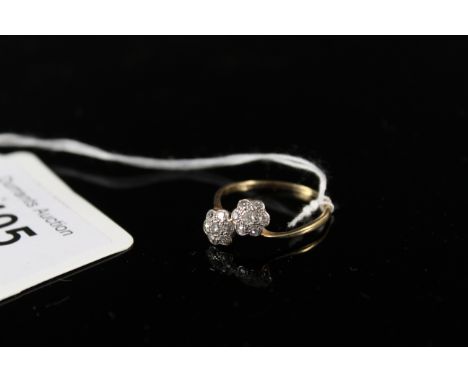 An 18ct gold diamond set crossover ring, the two flower heads each set with seven small diamonds, size P 1/2