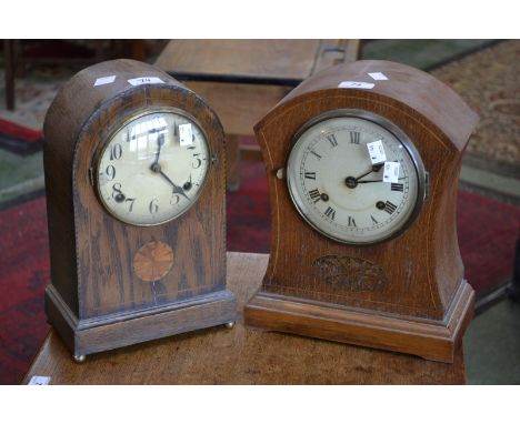 An Edwardian oak inlaid mantel clock; another similar arched mantel clock (2)