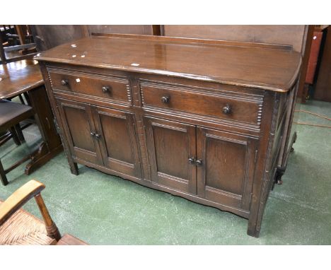 An Ercol style sideboard, oversailing top, two short drawers over four panel door cupboard, stile supports.