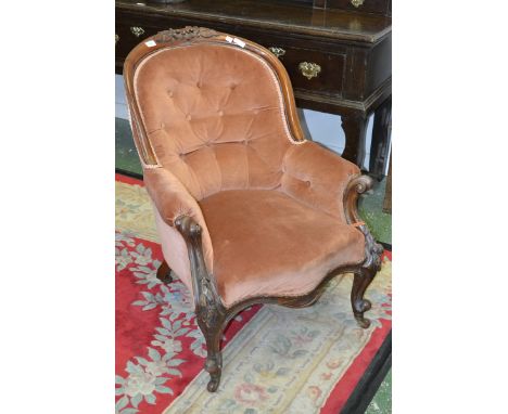 A Victorian mahogany button back armchair, floral carving to top rail, padded arms, serpentine stuffed overseat, carved cabri