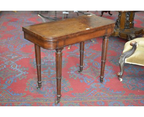 An early 19th century mahogany card table, fold over top enclosing green baize playing surface, tapering supports, brass cast