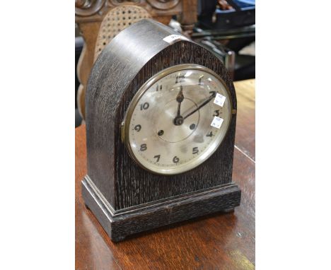 An arched ebonised mantel clock, silvered dial, Arabic numerals, twin winding holes, 33cm high, early 20th century