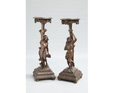 A PAIR OF CONTINENTAL CARVED FIGURAL STANDS, 19TH CENTURY,&nbsp;each with circular top above a tree trunk carved stem and the