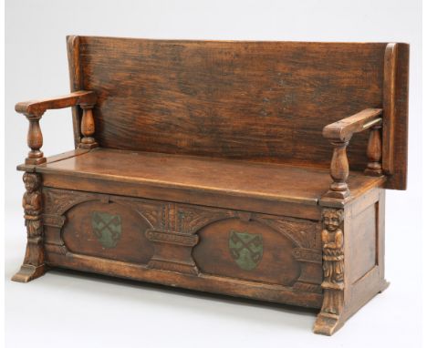 A LATE VICTORIAN OAK MONKS BENCH, the box seat with cross key crests and figural pilasters. 152cm long