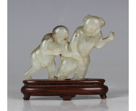 A Chinese pale celadon jade figure, 20th century, carved and pierced with two walking figures, the mottled stone with black/g