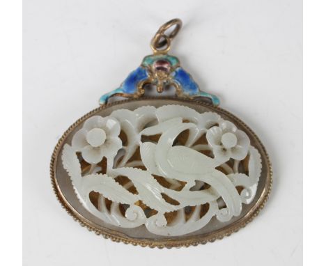 A Chinese silver gilt and enamelled set jade plaque pendant, the pale celadon panel carved and pierced with bird and flowers,