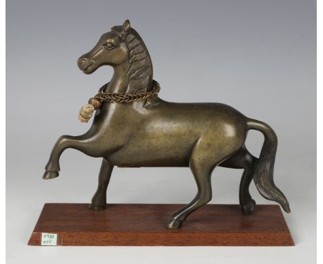 A Tibetan cast bronze figure of a healing horse, probably 16th century, modelled standing with left front leg raised, wearing