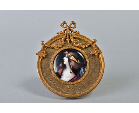 AN EARLY 20TH CENTURY FRENCH LIMOGES STYLE ENAMEL PORTRAIT PLAQUE OF A LADY, with ornate head dress, circular, within an ease