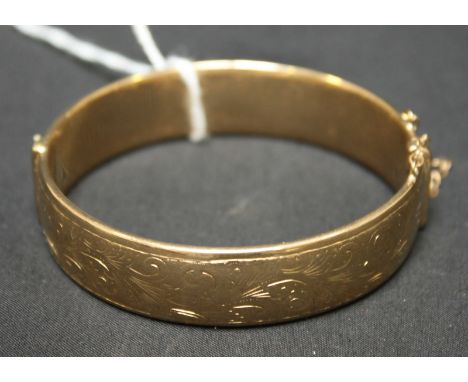 A 9ct gold hollow stiff hinged bangle with engraved decoration. Approx. 38.5 grams.