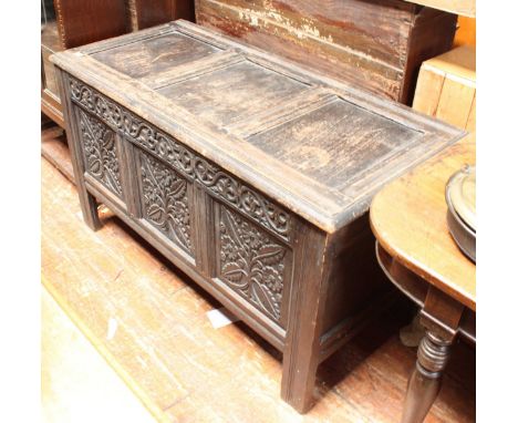 An 18th century stained oak coffer, of frame-and-panel construction, the frieze and three panels with floral foliate carving,