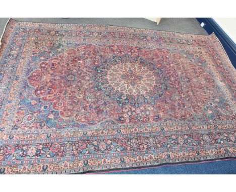 A large Persian red ground floral carpet, decorated all over with flowers and multiple floral borders.