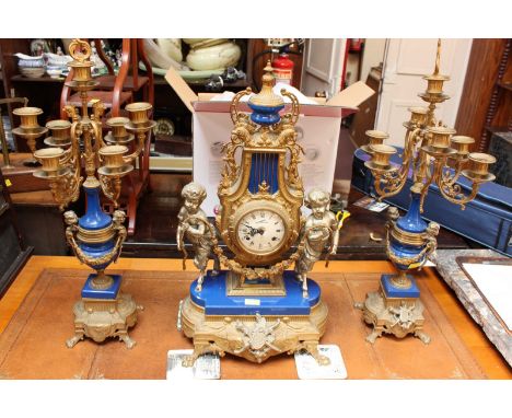 A Continental gilt metal and blue enamel clock garniture comprising a mantel clock with eight day movement striking on a bell