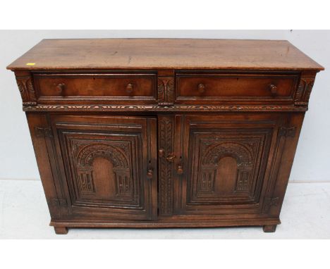 An 18th century style oak dresser base, the plain top over two short drawers with carved panel doors below, turned wooden han