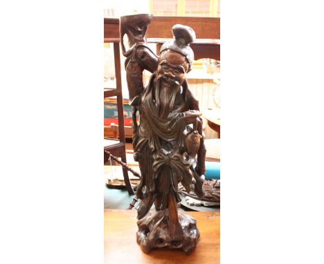 A Chinese carved hard wood figural table lamp, carved as a fisherman on a naturalistic base. 61 cm high.