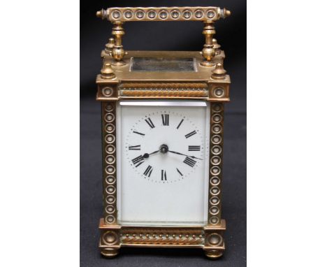 An early 20th century brass cased carriage clock, the cased decorated with roundels, white enamel dial with black Roman numer
