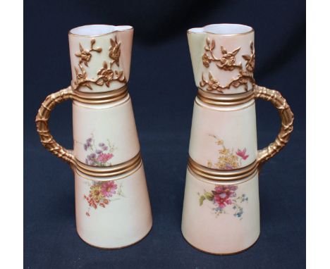 A pair of Victorian Royal Worcester blush ivory claret jugs, the tapering ringed bodies painted with flowers and entwined han