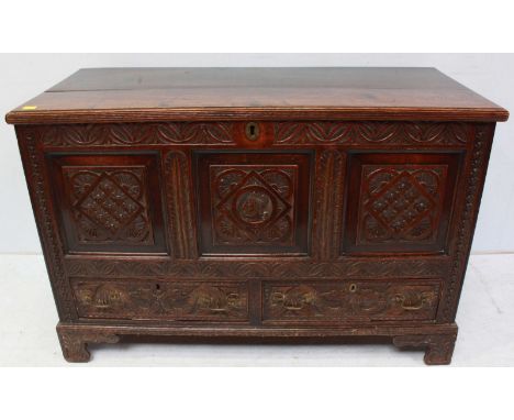 An 18th century oak blanket chest, the front with ornately carved panels decorated with flowers and a portrait bust over two 