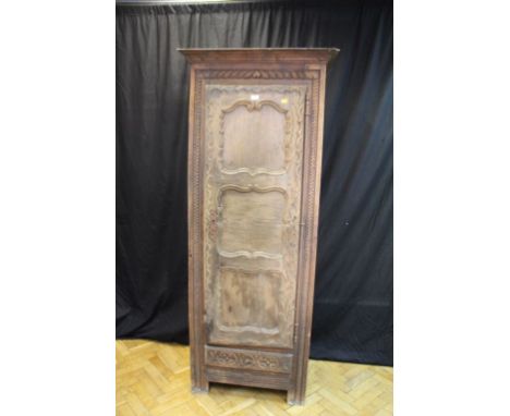 A 19th century continental walnut armoire, having a moulded cornice over leaf carved frieze and panelled door enclosing provi