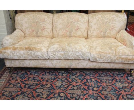 A 20th century three person salon settee, upholstered in floral print on turned fore legs and brass castors, 210 cm wide