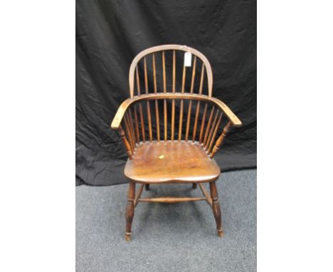 An early 19th century elm and ash hoop and stick back Windsor armchair, with saddle seat, raised on turned supports, tied by 