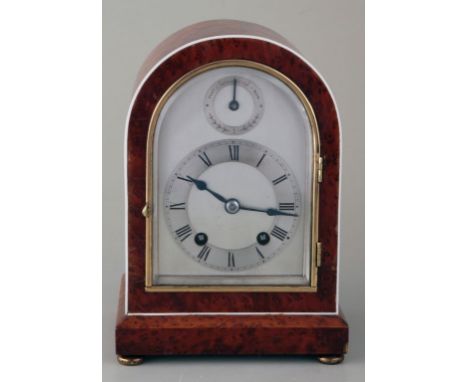 A 1920s eight day arch topped mantel clock, with ivorine strung amboyna case, the silvered dial with advance and retard indic