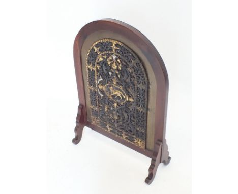A mahogany framed arch top firescreen with applied cast iron gilt and silvered panel 