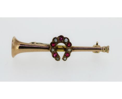 An Edwardian 9ct gold brooch in the form of a hunting horn set with a horseshoe studded with rubies and seed pearls, 4.2cm lo