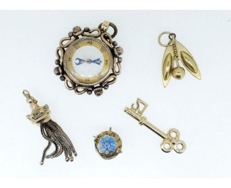 A gold plated compass form fob and four various gold plated charms 