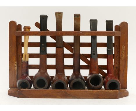 A collection of six briar pipes in a gate stand, including, Candy, Hull and Carly Magic Inch