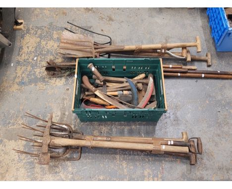 An assortment of gardening and agricultural tools, bundled together with a collection of miscellaneous tools.