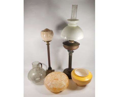 A collection of lamps and lampshades, to include, an oil lamp with brass stem and mid-century style shade, alongside a pink m