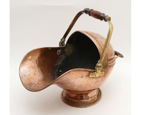 An Edwardian brass and copper coal helmet, having turned mahogany handles.