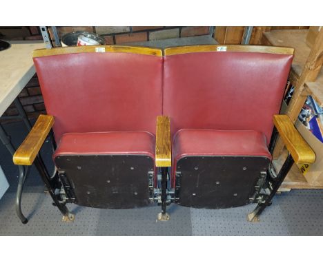 A pair of cinema/theatre stall seats, the fold up seats upholstered in burgundy faux leather, with curved wooden backrests.